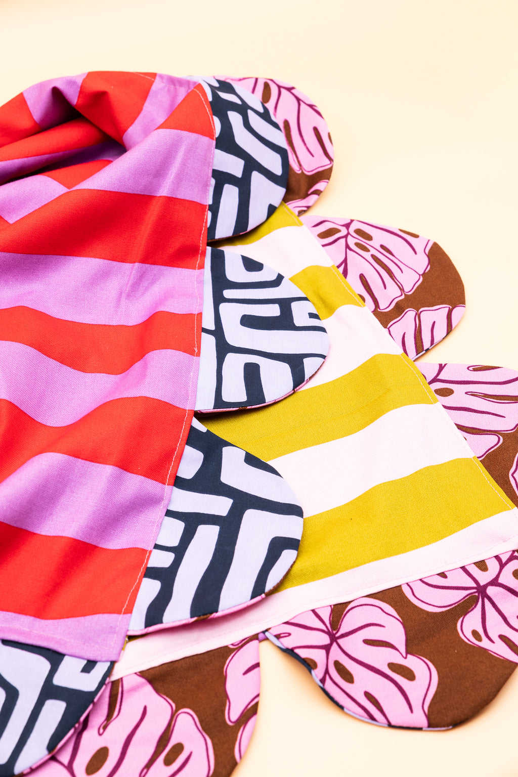 Both sides of the peachpicklepear reversible scallop tablecloth showing monstera and geometric print colourways